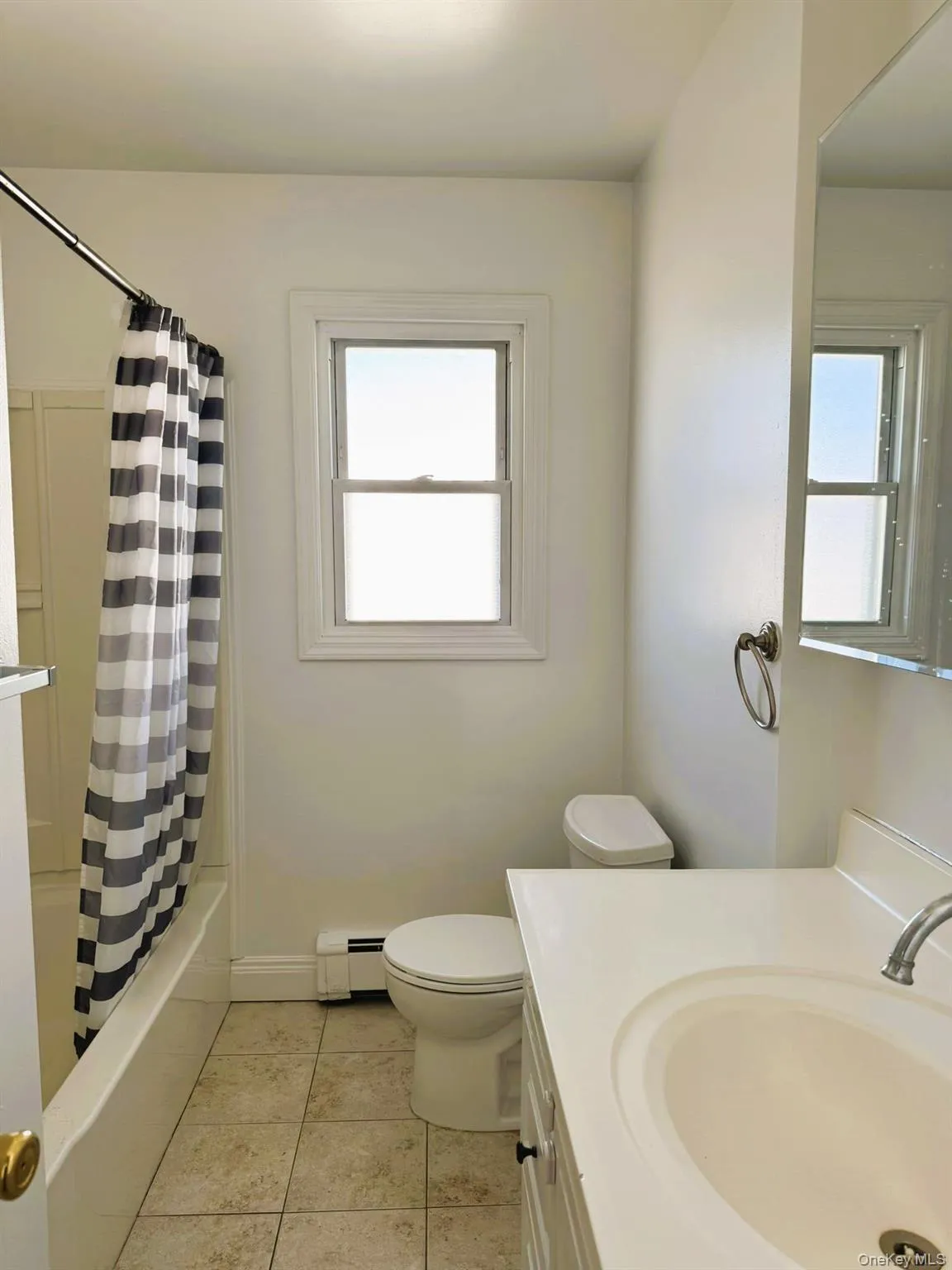 Bathroom featuring vanity, light tile patterned floors, plenty of natural light, and shower / tub combo Bathroom featuring vanity, light tile patterned floors, plenty of natural light, and shower / tub combo