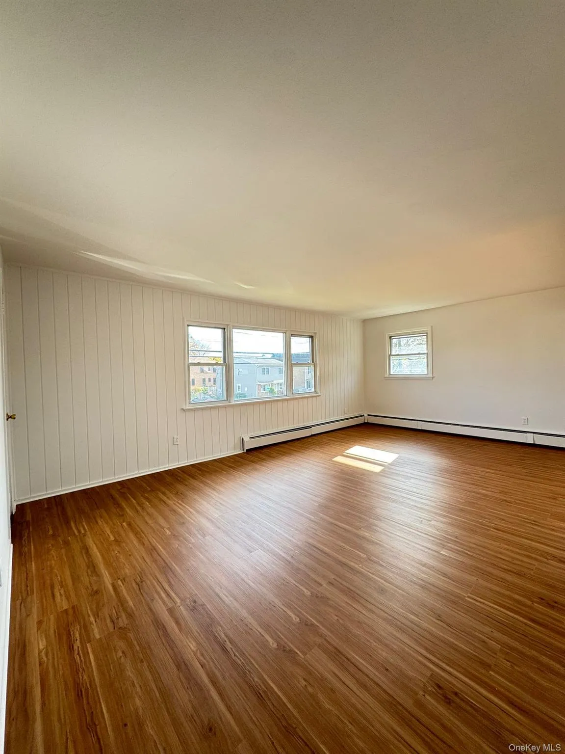 Spare room featuring wood finished floors and a baseboard radiator Spare room featuring wood finished floors and a baseboard radiator