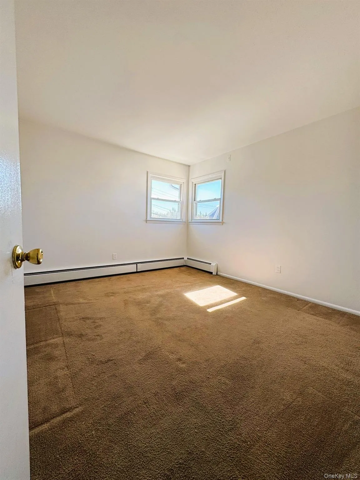 Carpeted empty room featuring baseboard heating and baseboards Carpeted empty room featuring baseboard heating and baseboards