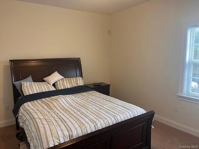 Bedroom featuring baseboards and dark colored carpet Bedroom featuring baseboards and dark colored carpet