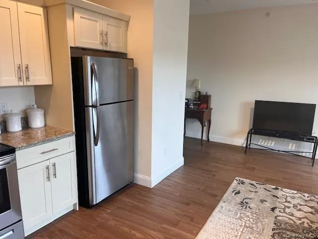 Kitchen featuring appliances with stainless steel finishes, white cabinetry, and dark wood-style flooring Kitchen featuring appliances with stainless steel finishes, white cabinetry, and dark wood-style flooring