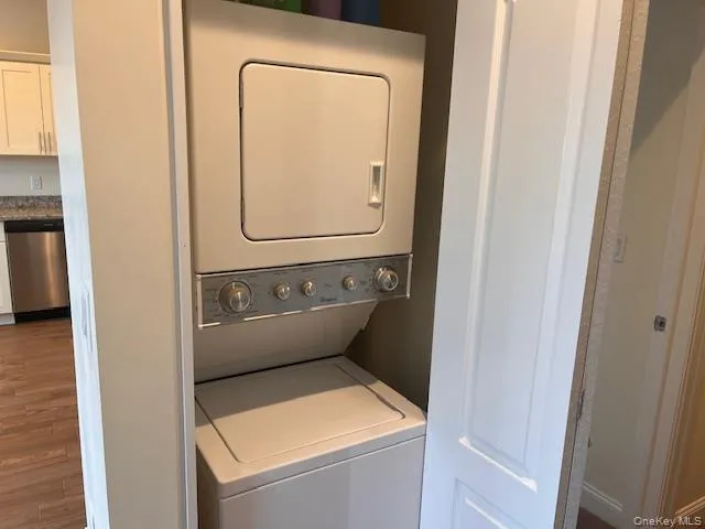 Laundry area with stacked washer / dryer and wood finished floors Laundry area with stacked washer / dryer and wood finished floors