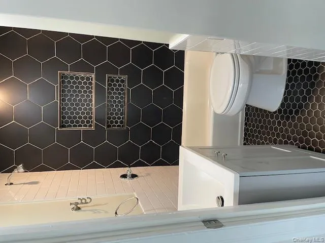 Bathroom with vanity, washtub / shower combination, and dark tile patterned floors Bathroom with vanity, washtub / shower combination, and dark tile patterned floors