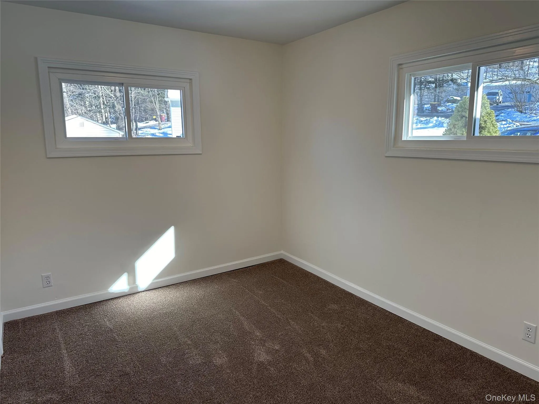 Spare room featuring baseboards and dark carpet Spare room featuring baseboards and dark carpet