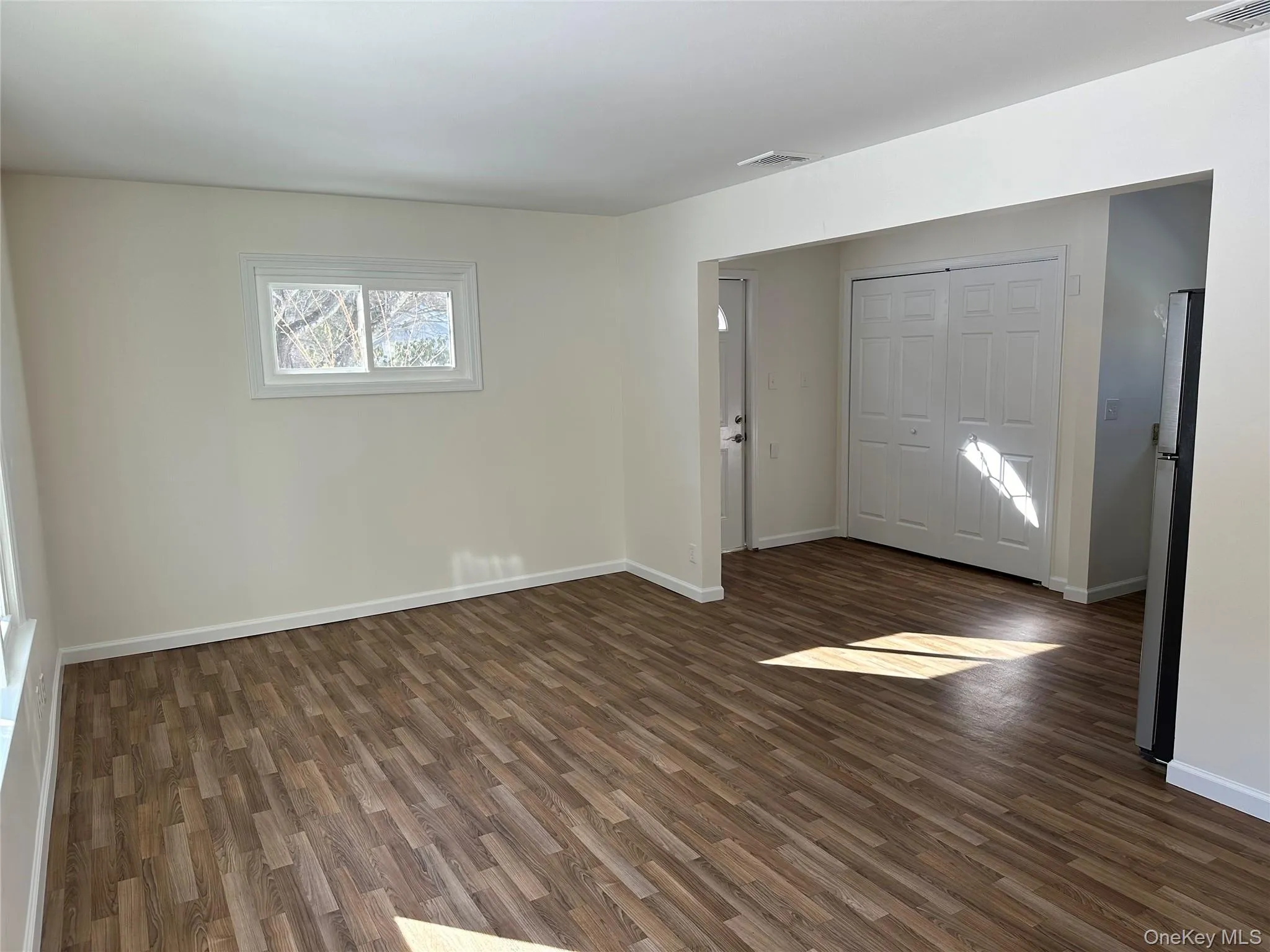 Unfurnished room with dark wood-style floors and baseboards Unfurnished room with dark wood-style floors and baseboards