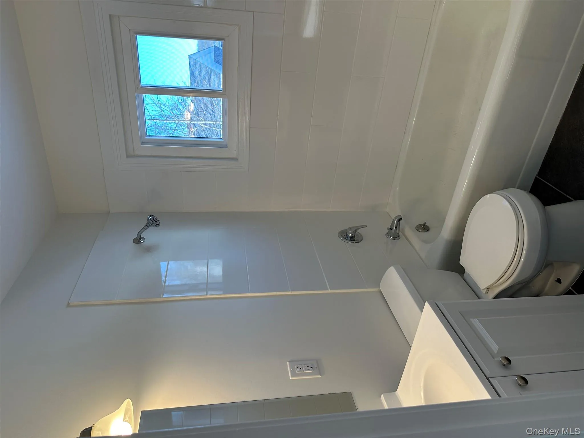Bathroom featuring washtub / shower combination, vanity, and dark tile patterned floors Bathroom featuring washtub / shower combination, vanity, and dark tile patterned floors