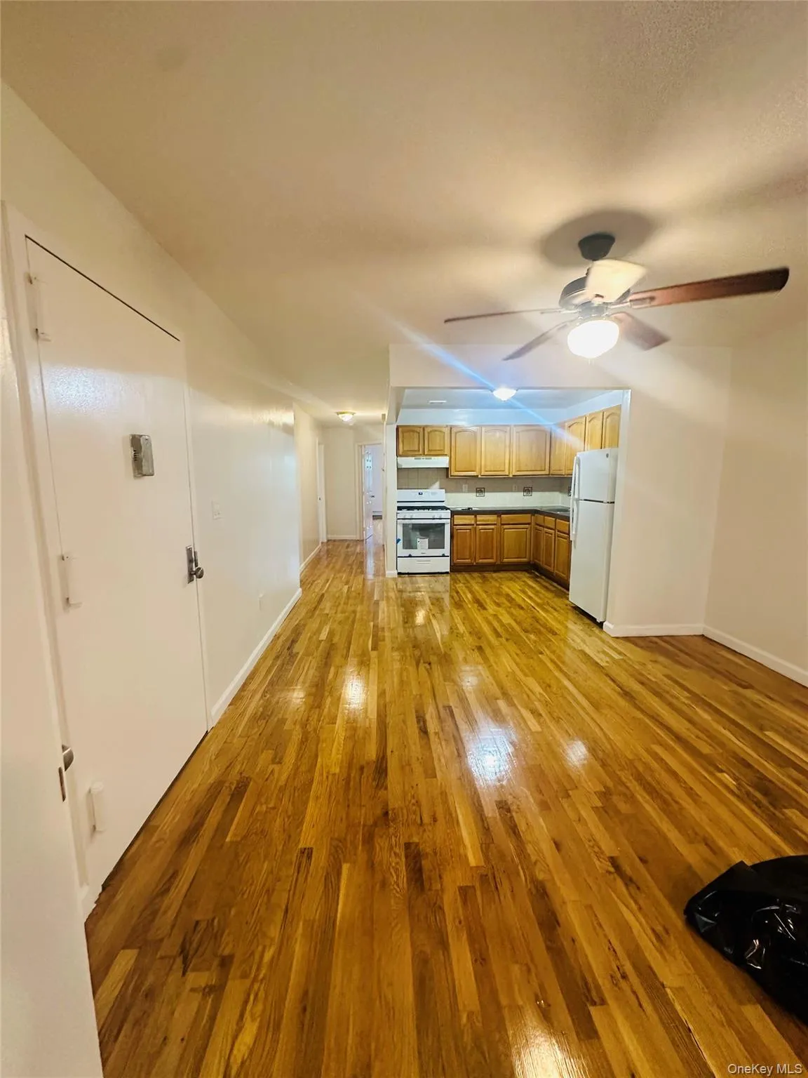 Kitchen with light wood-type flooring, white appliances, brown cabinetry, a ceiling fan, and under cabinet range hood Kitchen with light wood-type flooring, white appliances, brown cabinetry, a ceiling fan, and under cabinet range hood