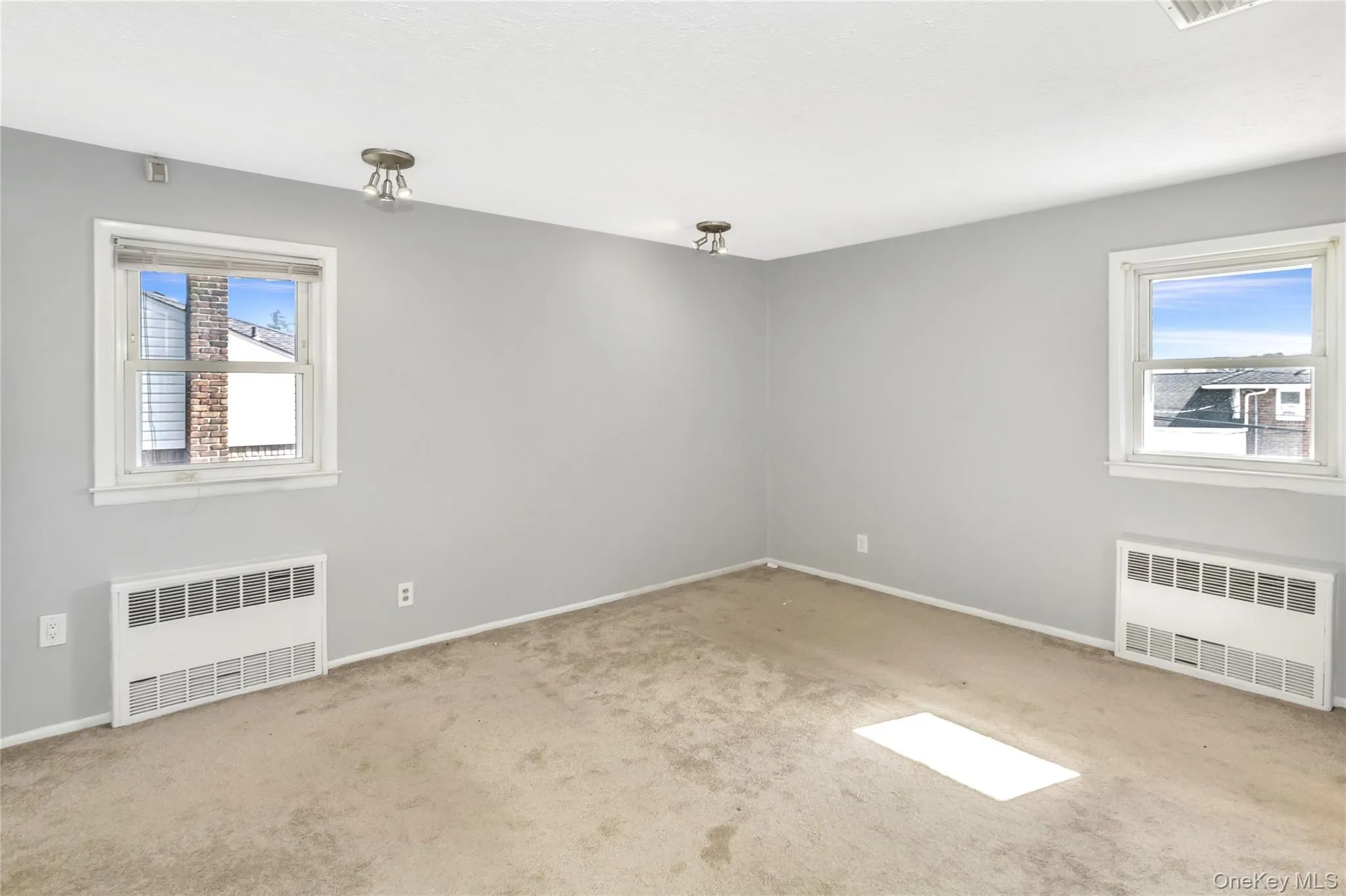 Empty room with radiator heating unit and light colored carpet Empty room with radiator heating unit and light colored carpet