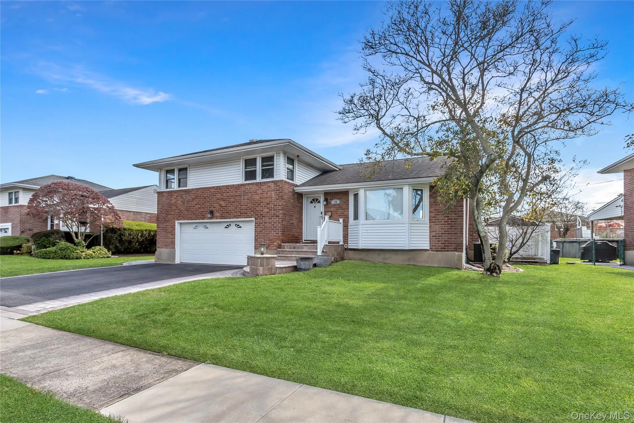 Tri-level home featuring brick siding, asphalt driveway, a front yard, and a garage Tri-level home featuring brick siding, asphalt driveway, a front yard, and a garage