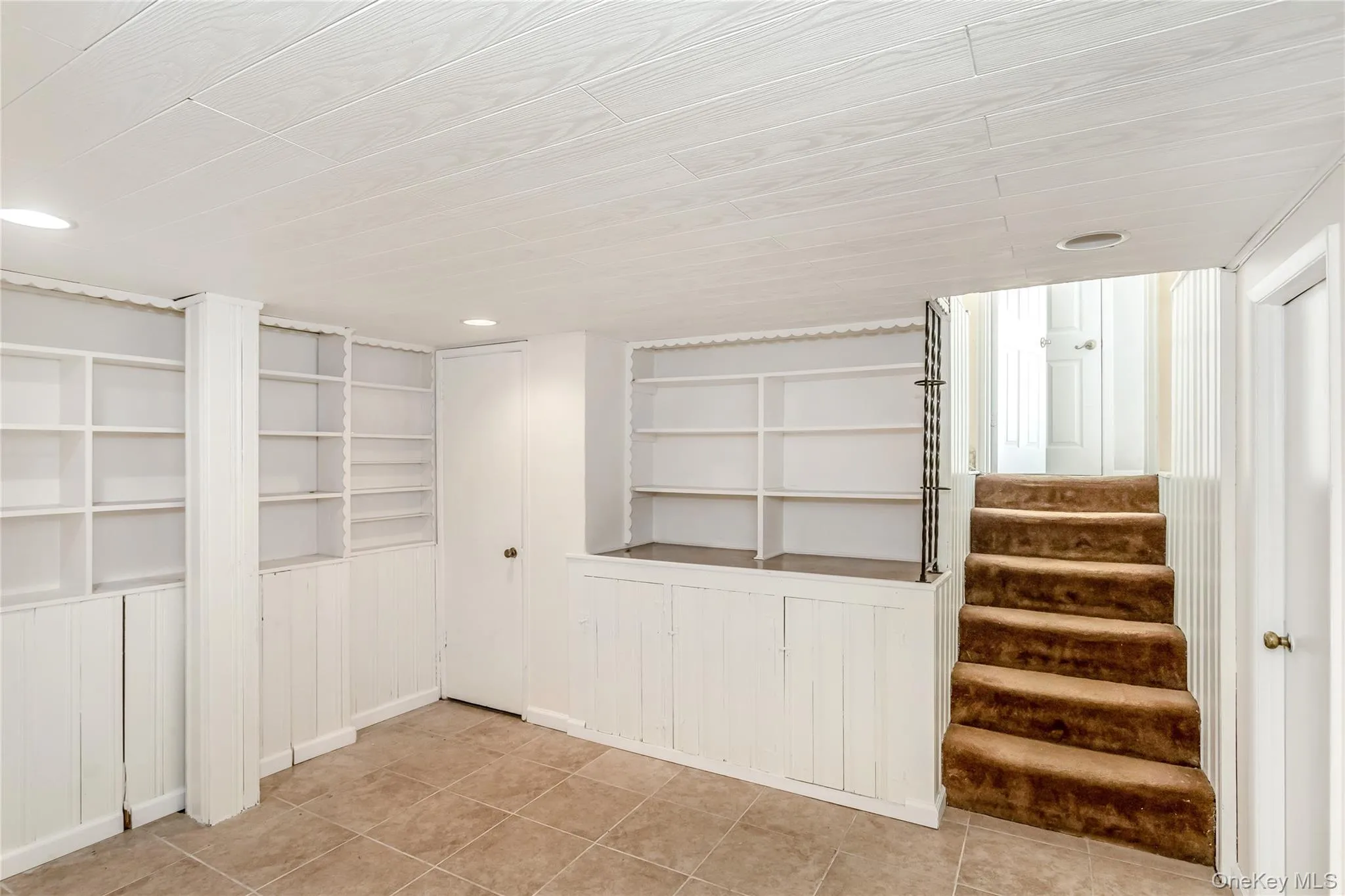 Finished below grade area featuring light tile patterned floors, built in features, stairway, and recessed lighting Finished below grade area featuring light tile patterned floors, built in features, stairway, and recessed lighting