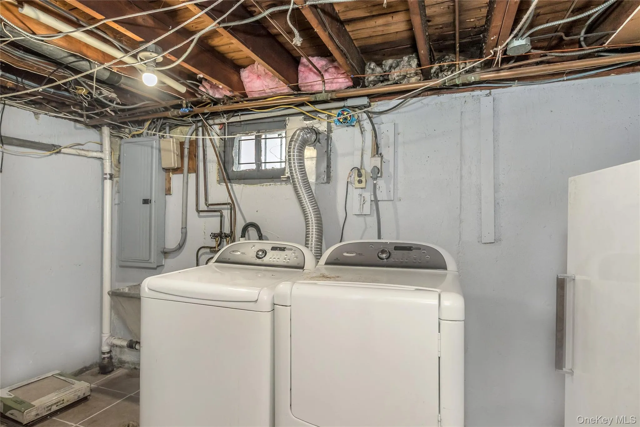Laundry area with electric panel, independent washer and dryer, and tile patterned flooring Laundry area with electric panel, independent washer and dryer, and tile patterned flooring