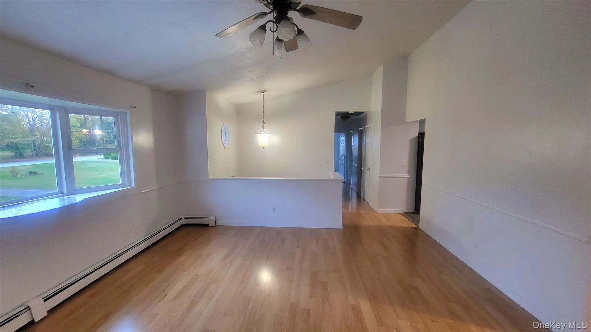 Spare room featuring light wood-style flooring, lofted ceiling, a baseboard heating unit, and a ceiling fan Spare room featuring light wood-style flooring, lofted ceiling, a baseboard heating unit, and a ceiling fan