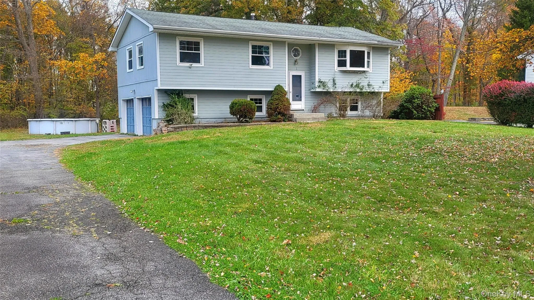 Split foyer home featuring a front lawn, a garage, and asphalt driveway Split foyer home featuring a front lawn, a garage, and asphalt driveway