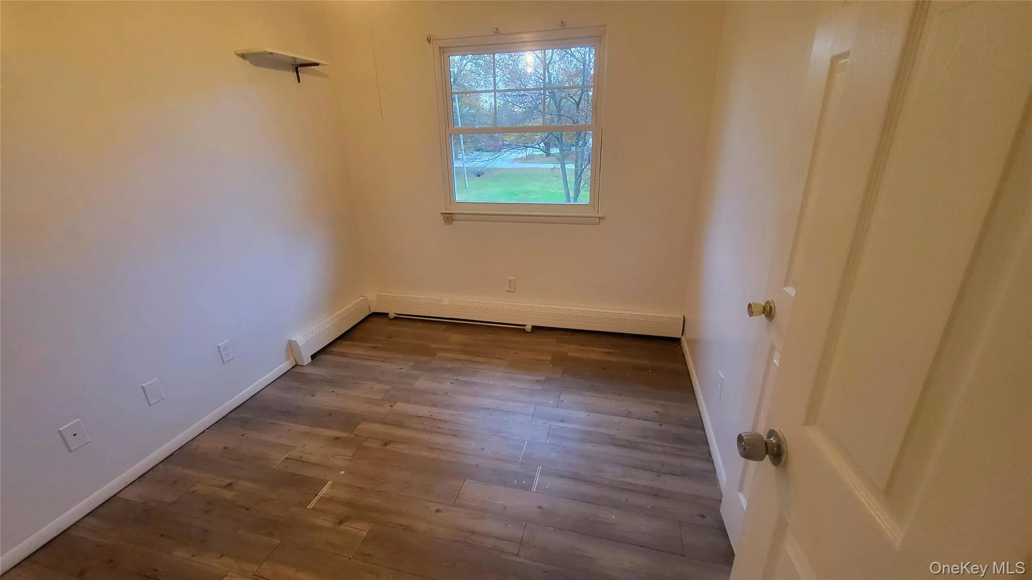 Empty room with dark wood finished floors and a baseboard radiator Empty room with dark wood finished floors and a baseboard radiator