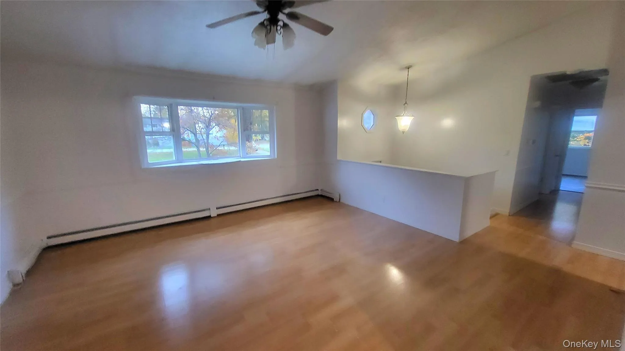 Unfurnished room with light wood finished floors, baseboard heating, a ceiling fan, and vaulted ceiling Unfurnished room with light wood finished floors, baseboard heating, a ceiling fan, and vaulted ceiling