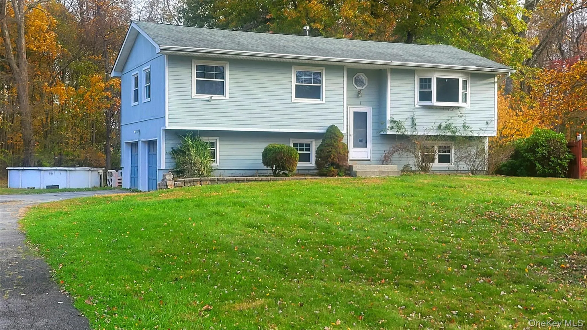 Raised ranch with asphalt driveway, a garage, a front yard, and a pool Raised ranch with asphalt driveway, a garage, a front yard, and a pool