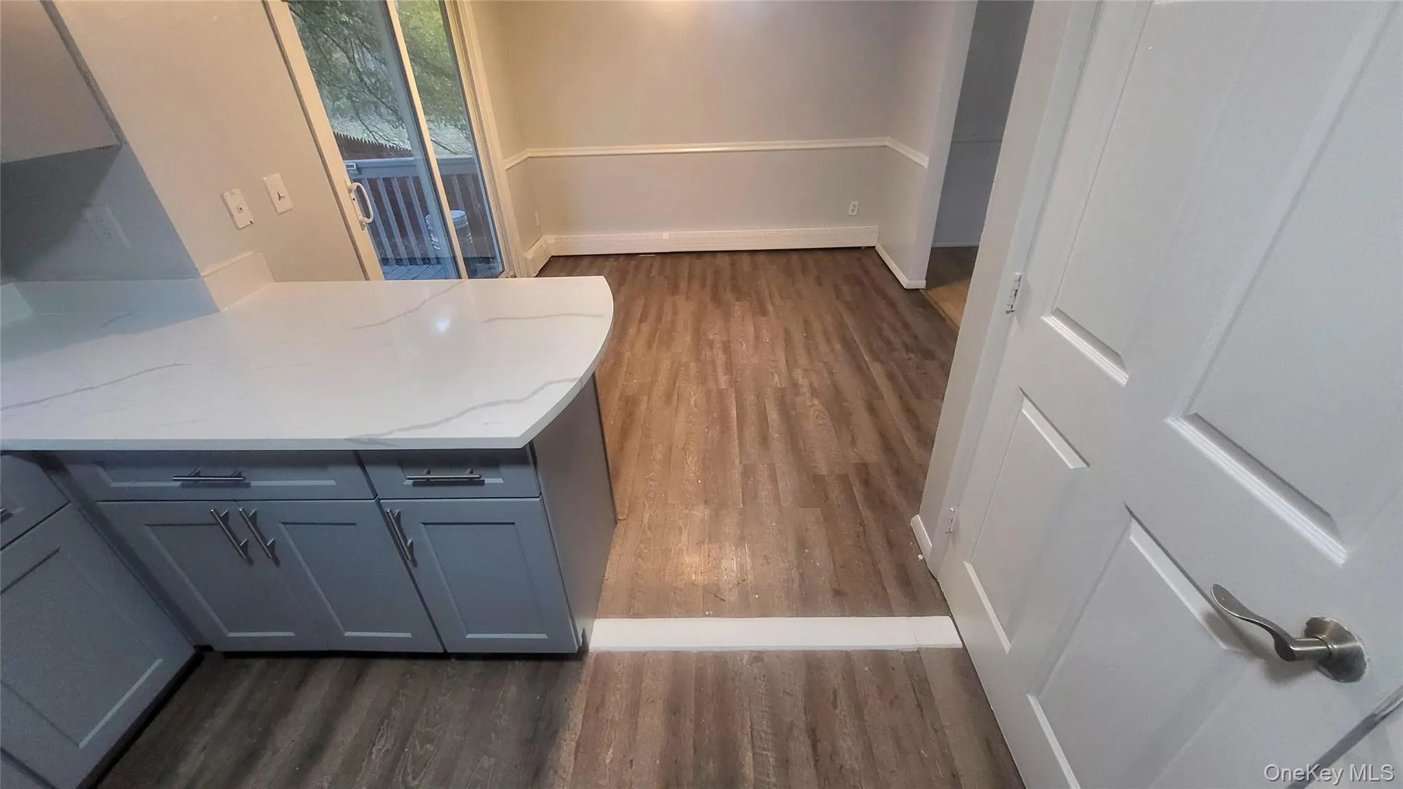 Unfurnished dining area with dark wood-type flooring and baseboards Unfurnished dining area with dark wood-type flooring and baseboards