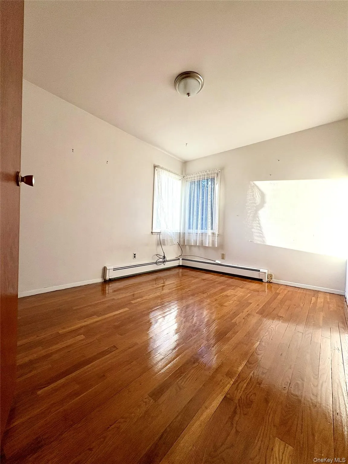 Empty room with light wood finished floors and baseboards Empty room with light wood finished floors and baseboards