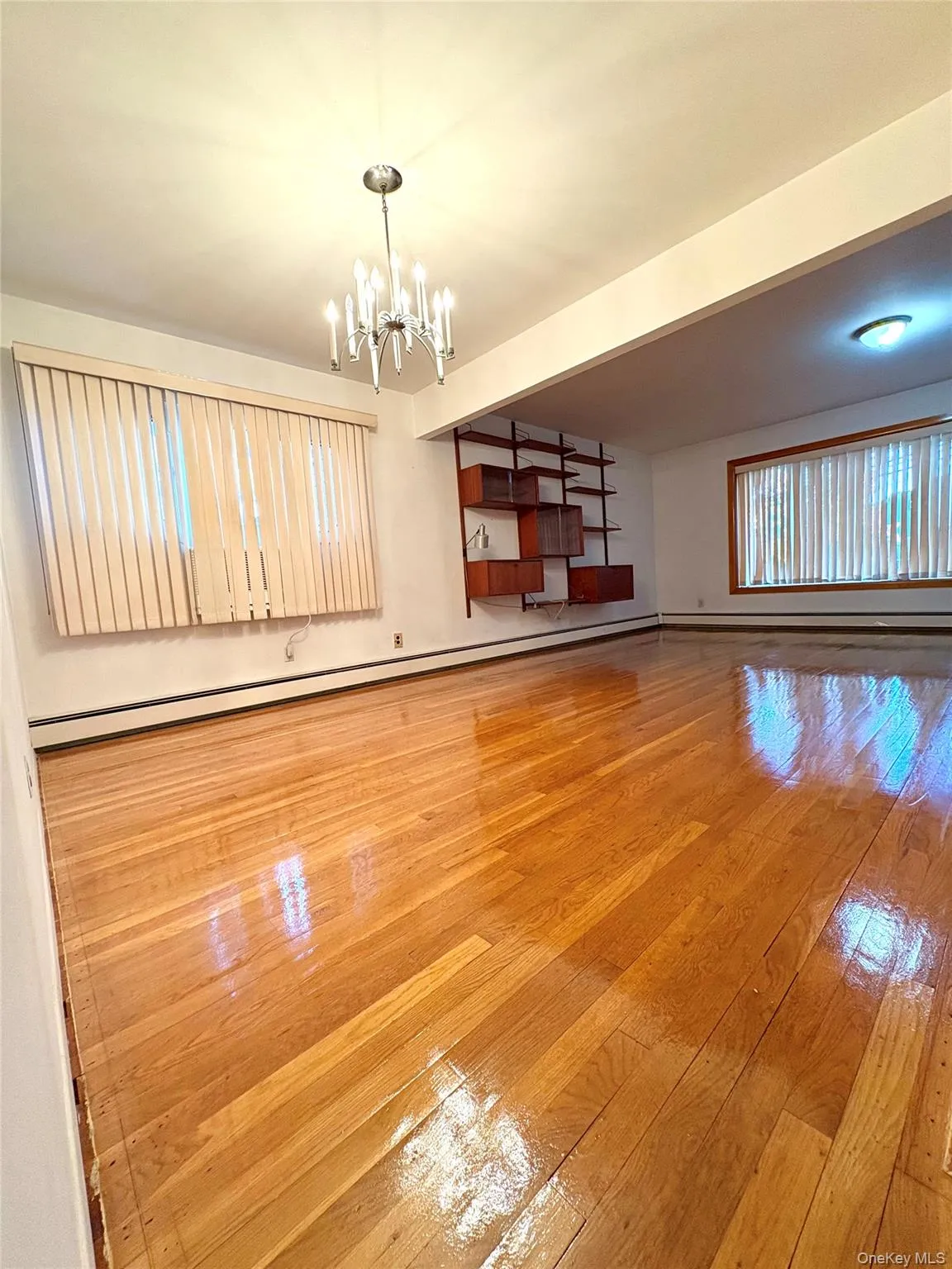 Unfurnished living room with light wood-style floors, a baseboard heating unit, and a chandelier Unfurnished living room with light wood-style floors, a baseboard heating unit, and a chandelier