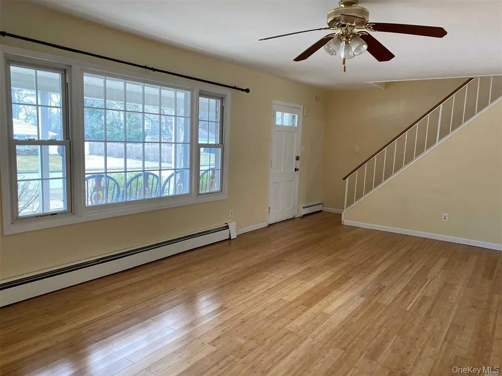 Foyer with baseboard heating, a ceiling fan, light wood-style floors, and stairway Foyer with baseboard heating, a ceiling fan, light wood-style floors, and stairway