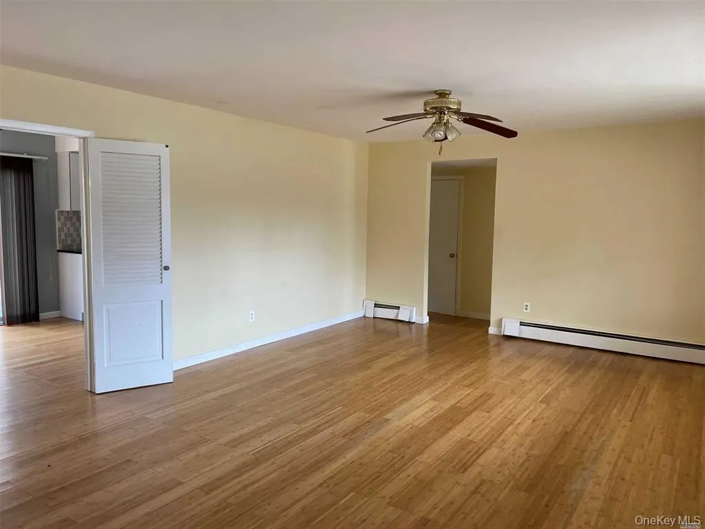 Unfurnished room featuring light wood-style flooring, a baseboard heating unit, and ceiling fan Unfurnished room featuring light wood-style flooring, a baseboard heating unit, and ceiling fan