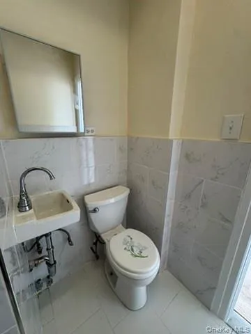 Half bath with tile walls, tile patterned flooring, and wainscoting Half bath with tile walls, tile patterned flooring, and wainscoting