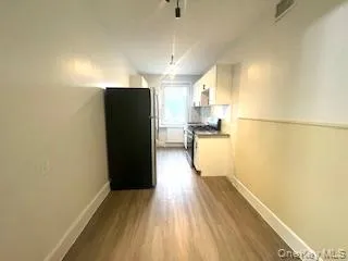 Kitchen featuring appliances with stainless steel finishes, white cabinetry, light wood finished floors, and dark countertops Kitchen featuring appliances with stainless steel finishes, white cabinetry, light wood finished floors, and dark countertops