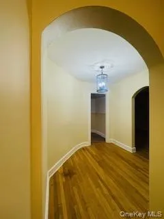 Corridor featuring arched walkways and wood finished floors Corridor featuring arched walkways and wood finished floors