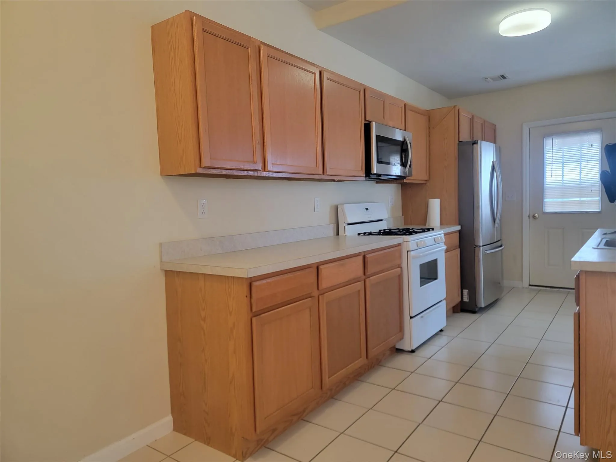 Kitchen featuring appliances with stainless steel finishes, light tile patterned floors, and light countertops Kitchen featuring appliances with stainless steel finishes, light tile patterned floors, and light countertops