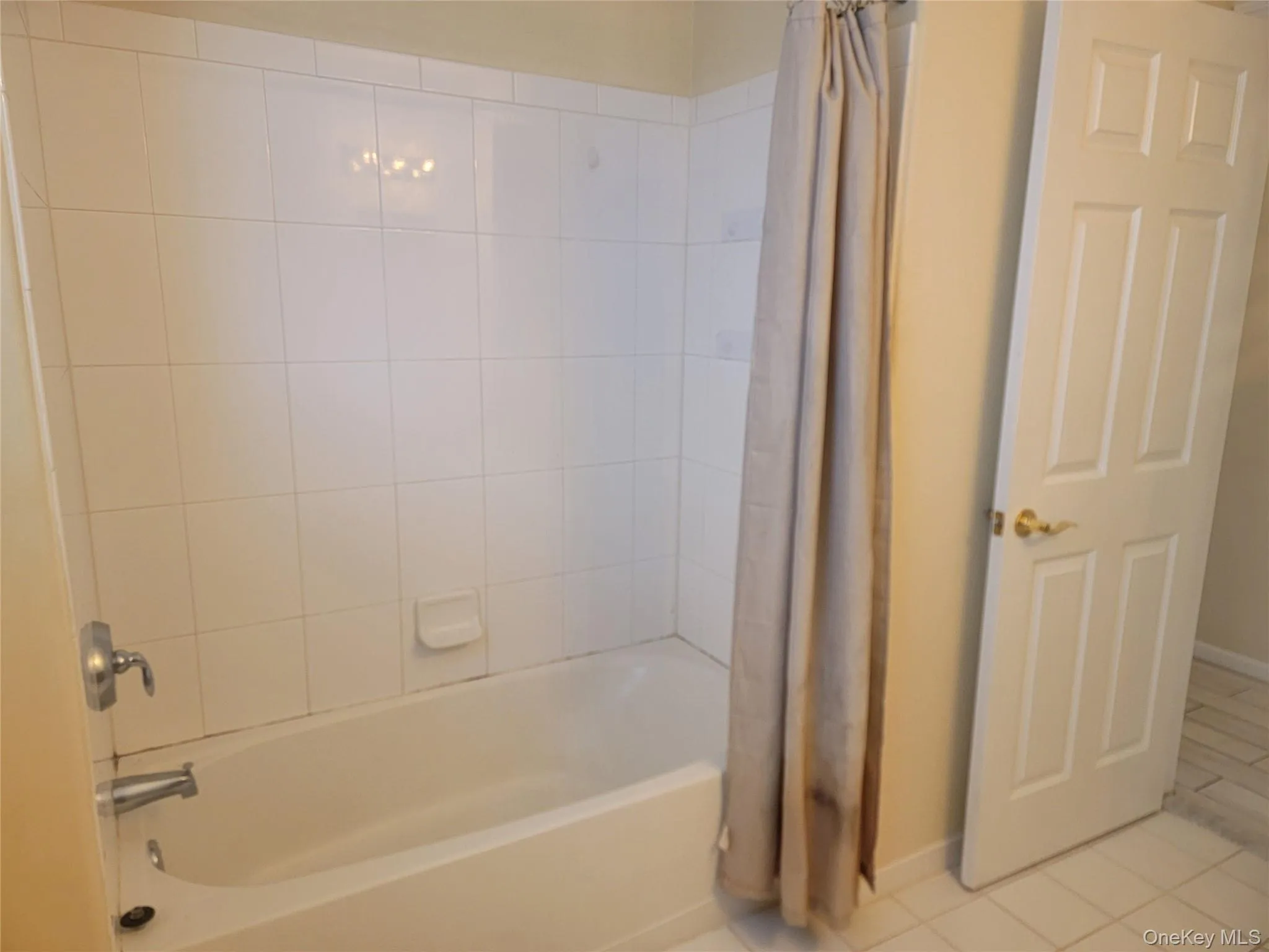 Full bathroom featuring tile patterned floors and shower / bath combo with shower curtain Full bathroom featuring tile patterned floors and shower / bath combo with shower curtain