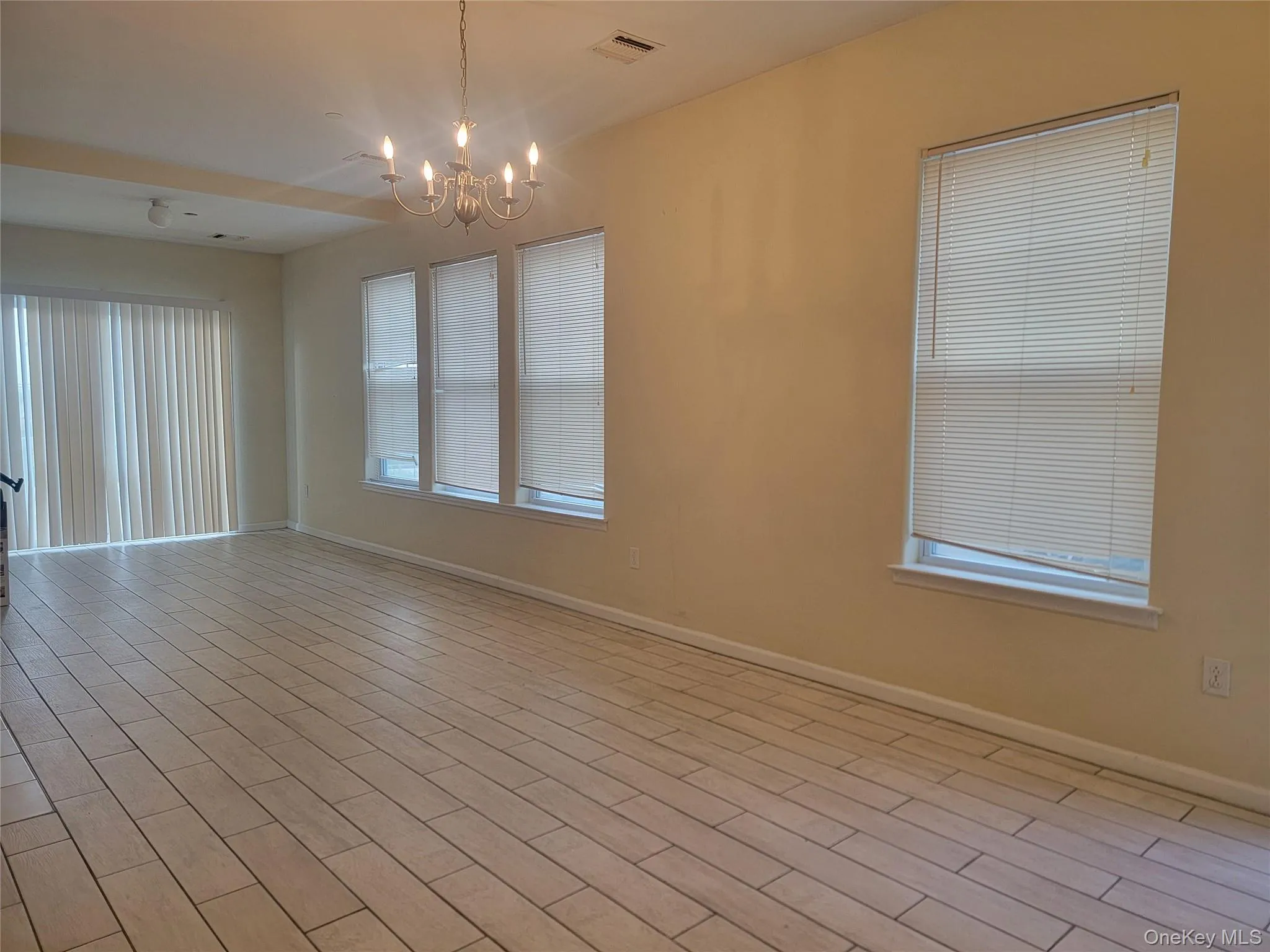 Spare room with light wood-style floors and a chandelier Spare room with light wood-style floors and a chandelier