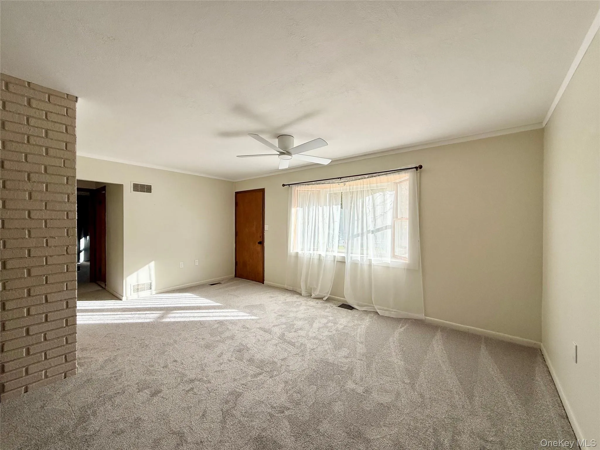 Carpeted living room featuring crown molding and a ceiling fan Carpeted living room featuring crown molding and a ceiling fan