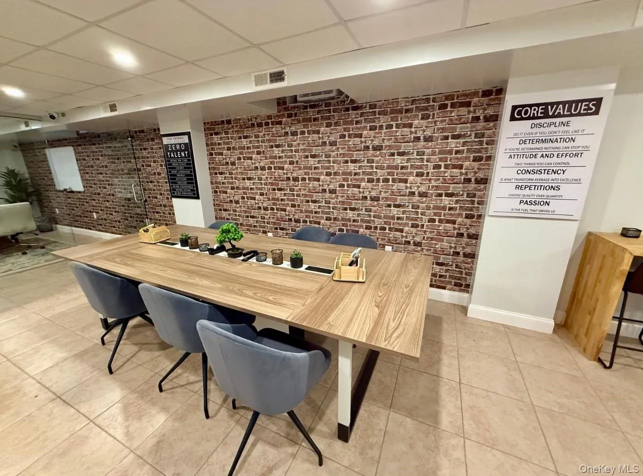 Dining area with brick wall, a drop ceiling, and light tile patterned floors Dining area with brick wall, a drop ceiling, and light tile patterned floors