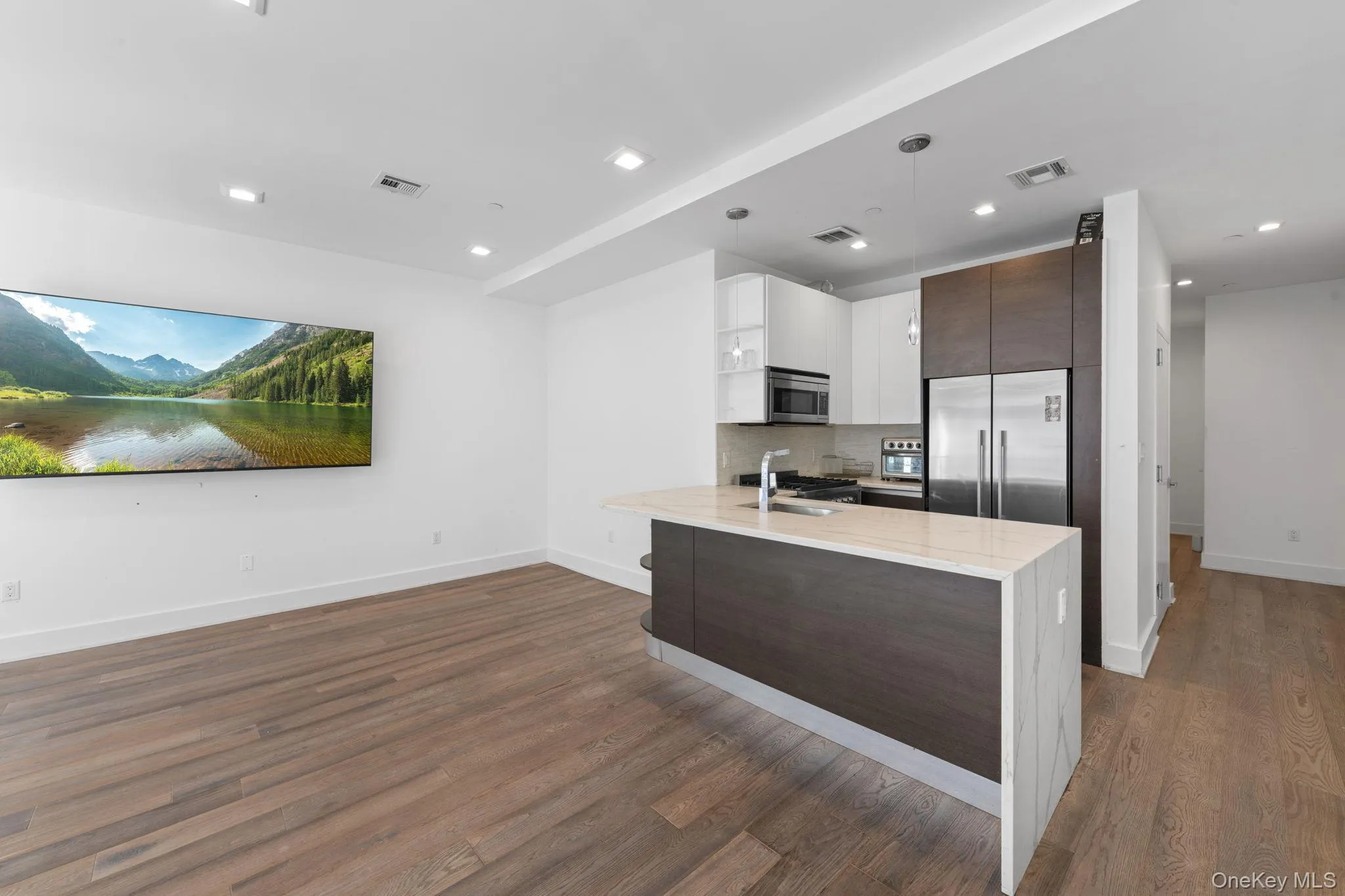 Kitchen with dark brown cabinetry, light stone countertops, hanging light fixtures, backsplash, and white cabinets Kitchen with dark brown cabinetry, light stone countertops, hanging light fixtures, backsplash, and white cabinets
