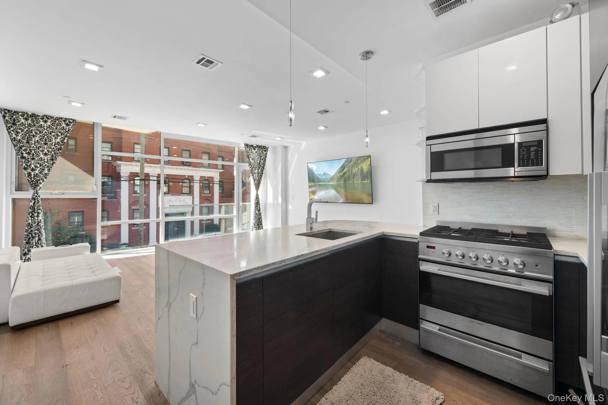 Kitchen featuring stainless steel appliances, modern cabinets, a peninsula, light stone countertops, and recessed lighting Kitchen featuring stainless steel appliances, modern cabinets, a peninsula, light stone countertops, and recessed lighting