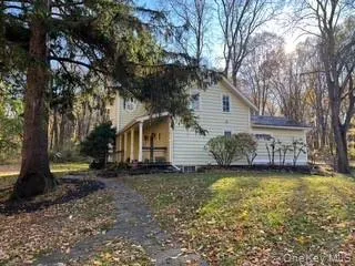 View of house from the front and side exterior featuring covered porch and a lawn View of house from the front and side exterior featuring covered porch and a lawn