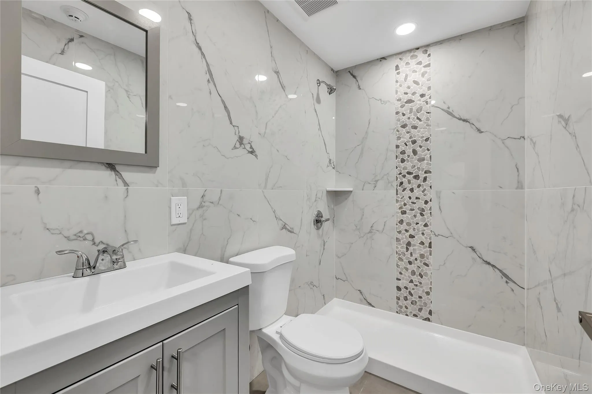 Bathroom with tile walls, vanity, a marble finish shower, and stone wall Bathroom with tile walls, vanity, a marble finish shower, and stone wall