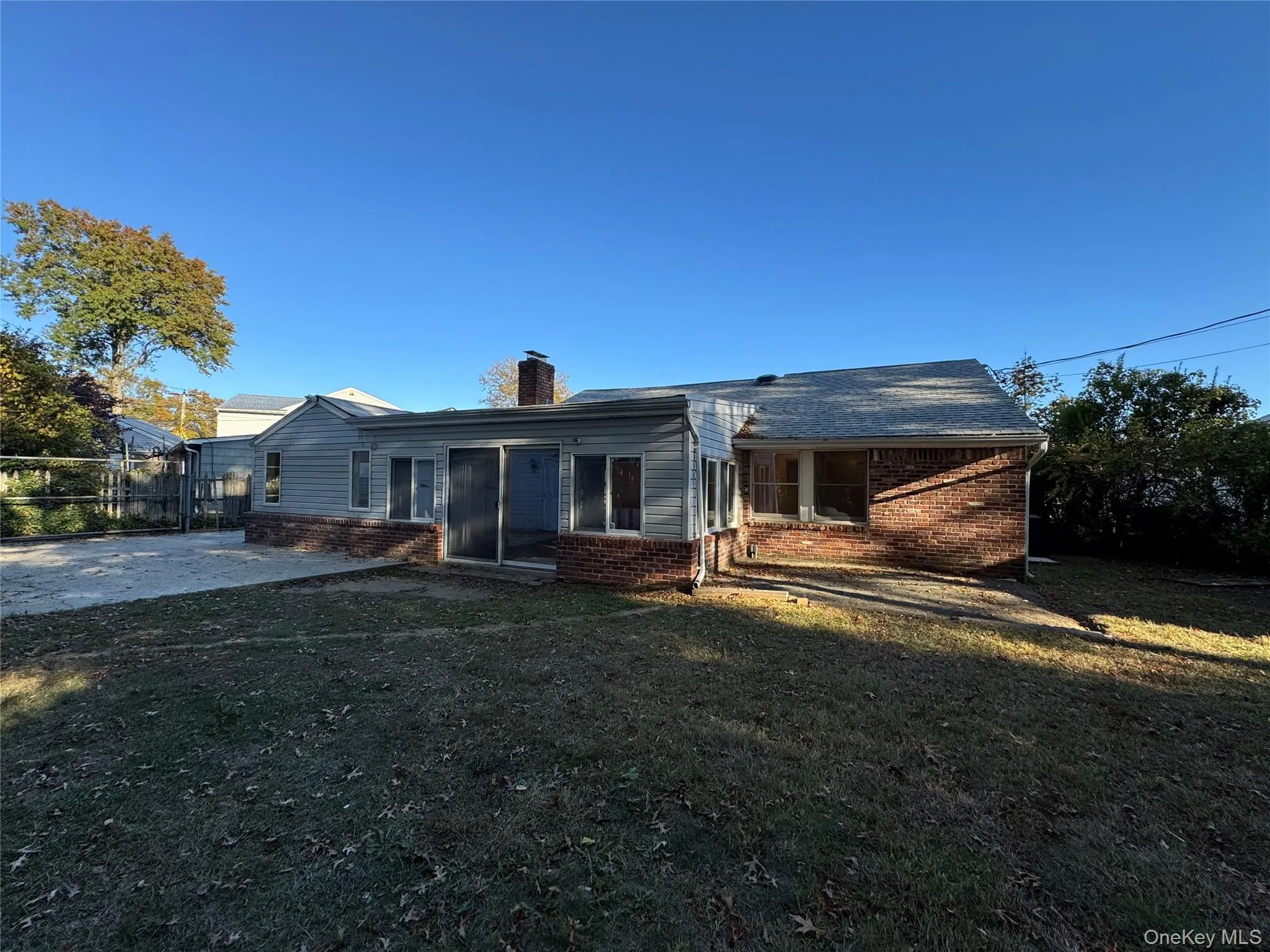 Rear view of property featuring brick siding, a private lawn, and a chimney. Rear view of property featuring brick siding, a private lawn, and a chimney.