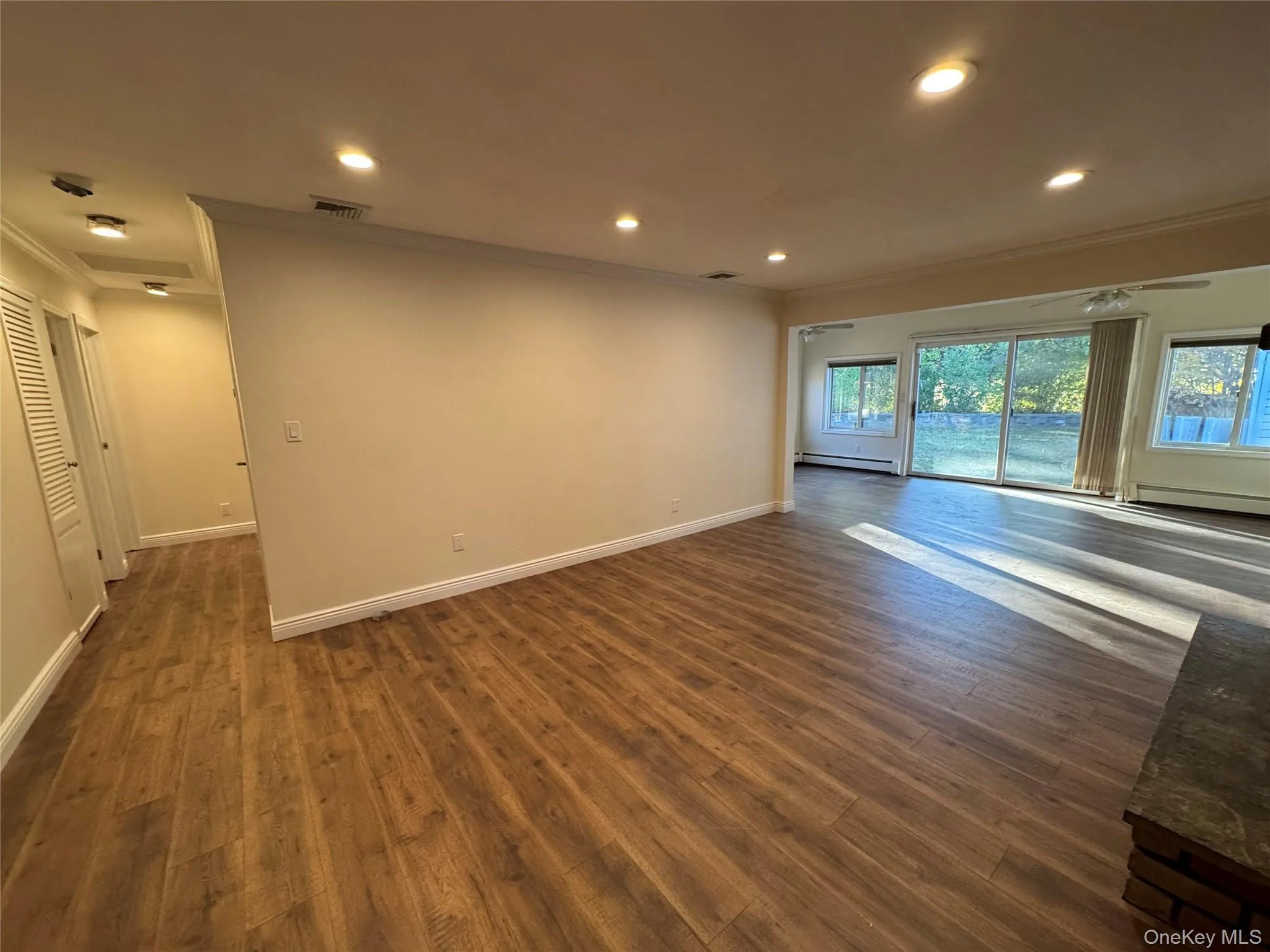 Unfurnished room featuring ornamental molding, recessed lighting, dark wood finished floors, and baseboard heating Unfurnished room featuring ornamental molding, recessed lighting, dark wood finished floors, and baseboard heating
