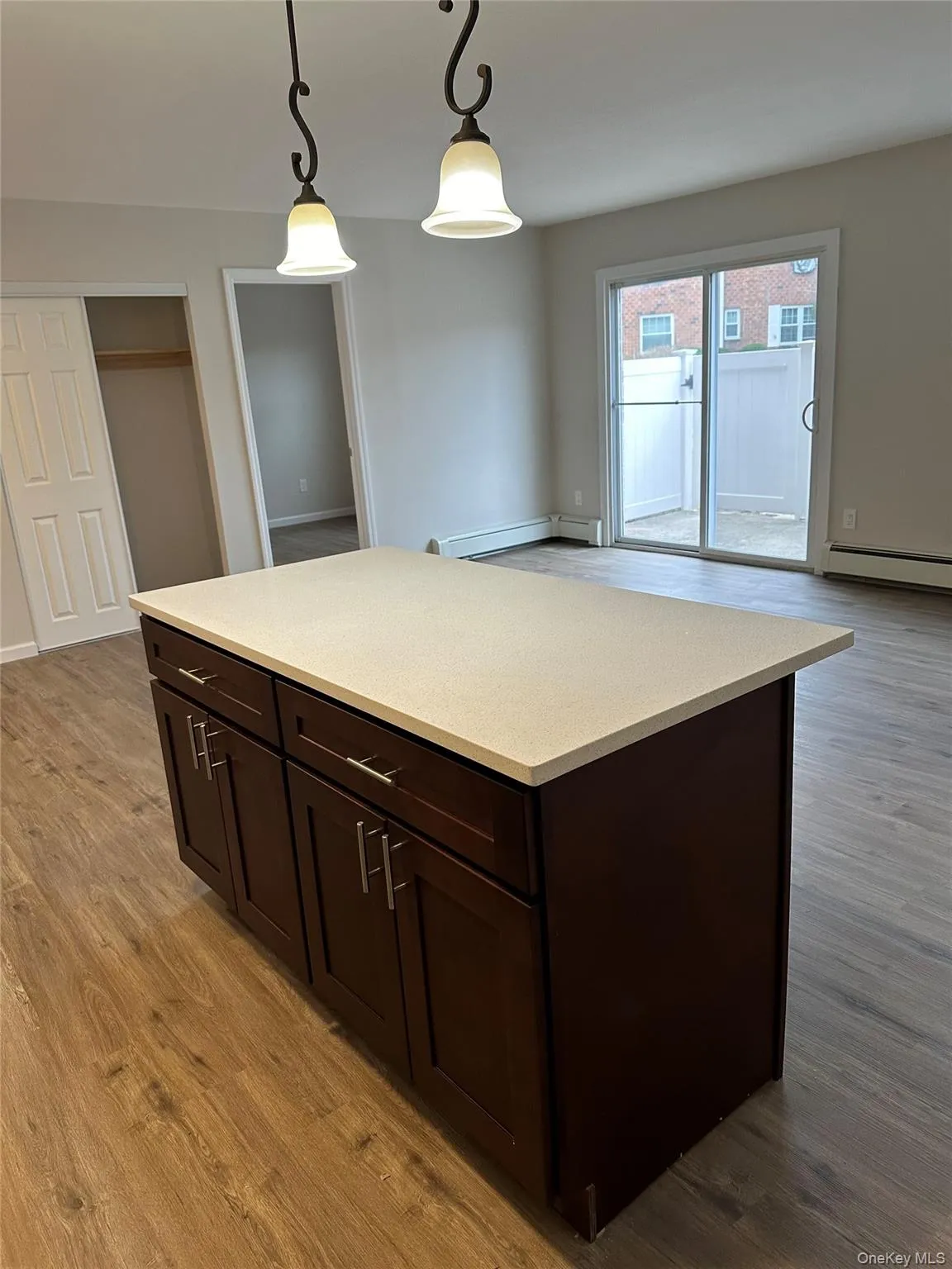 Kitchen with dark brown cabinetry, a center island, pendant lighting, a baseboard radiator, and light wood-style flooring Kitchen with dark brown cabinetry, a center island, pendant lighting, a baseboard radiator, and light wood-style flooring