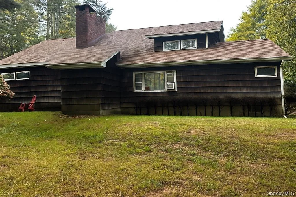 Back of property with a yard, a chimney, and roof with shingles Back of property with a yard, a chimney, and roof with shingles
