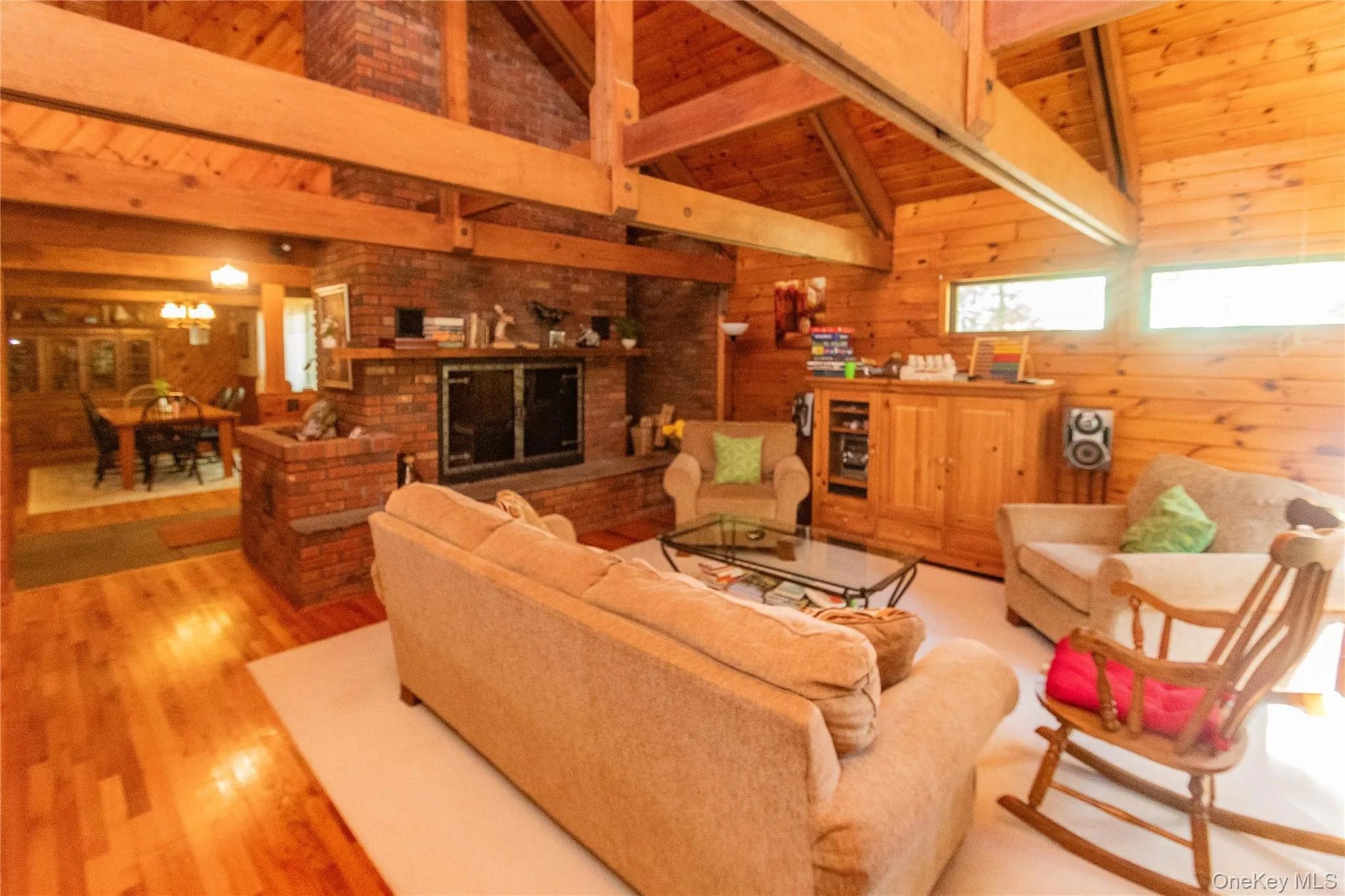 Living area with wooden walls, a wood ceiling with exposed beams, light wood-type flooring, and high vaulted ceiling Living area with wooden walls, a wood ceiling with exposed beams, light wood-type flooring, and high vaulted ceiling