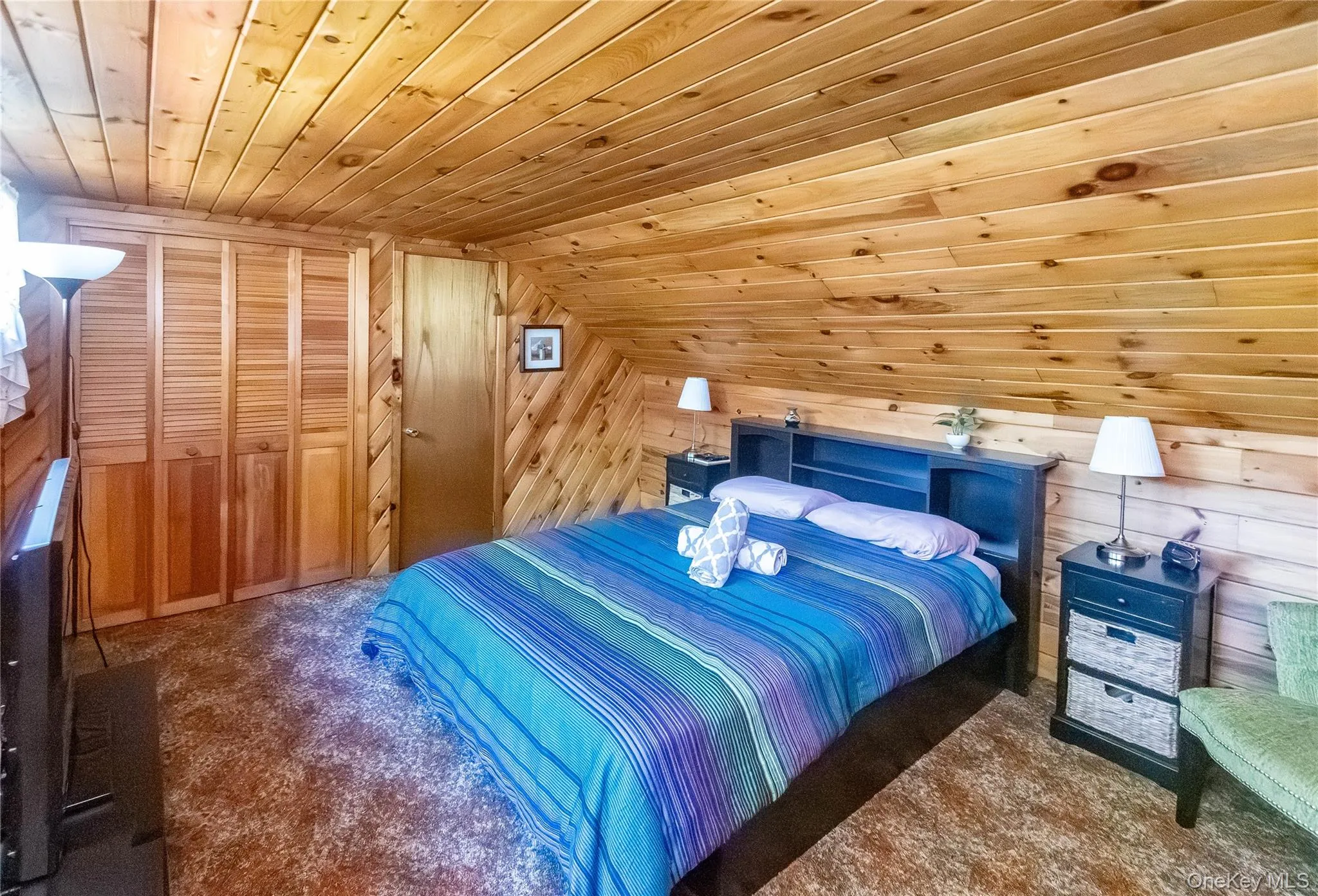 Bedroom featuring wood ceiling, a closet, wood walls, lofted ceiling, and carpet floors Bedroom featuring wood ceiling, a closet, wood walls, lofted ceiling, and carpet floors