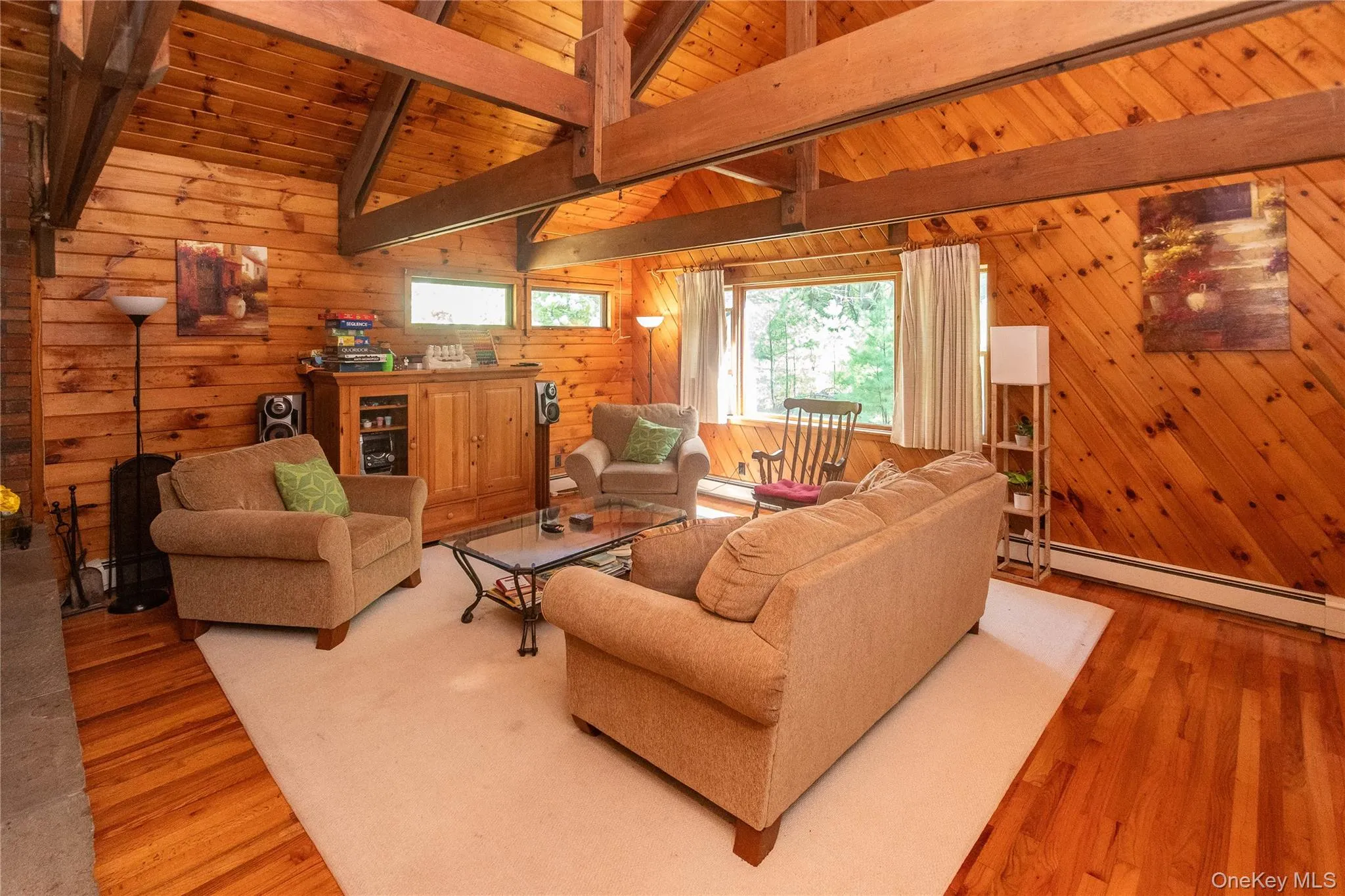Living area featuring a baseboard radiator, light wood-type flooring, wood ceiling, and wooden walls Living area featuring a baseboard radiator, light wood-type flooring, wood ceiling, and wooden walls