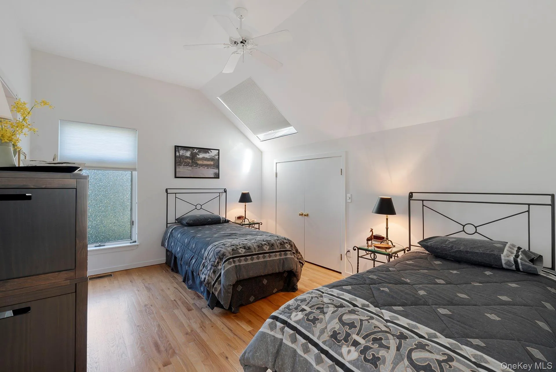Bedroom with lofted ceiling, light wood-type flooring, a ceiling fan, and a skylight Bedroom with lofted ceiling, light wood-type flooring, a ceiling fan, and a skylight