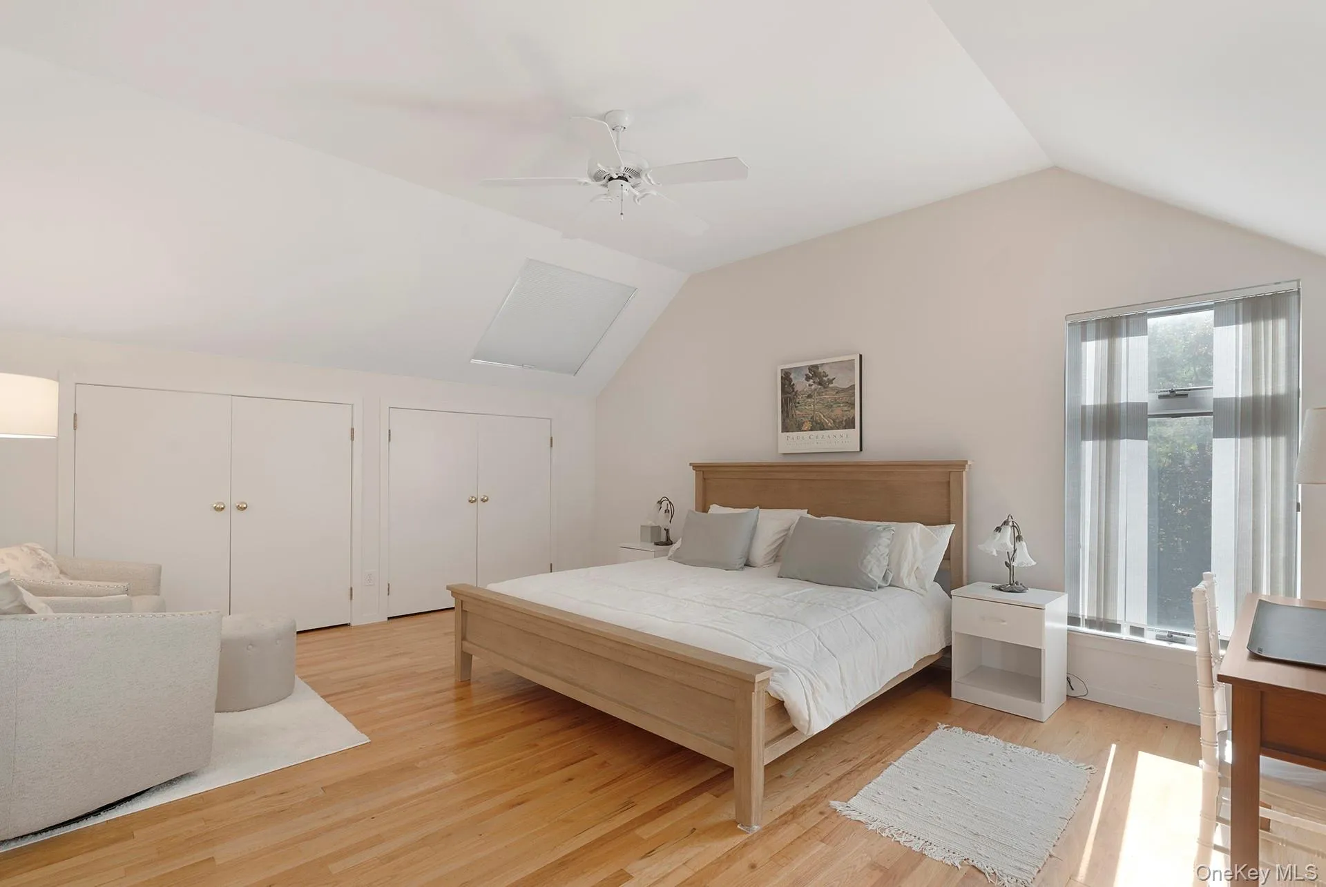 Bedroom with vaulted ceiling, two closets, light wood-style floors, and a ceiling fan Bedroom with vaulted ceiling, two closets, light wood-style floors, and a ceiling fan
