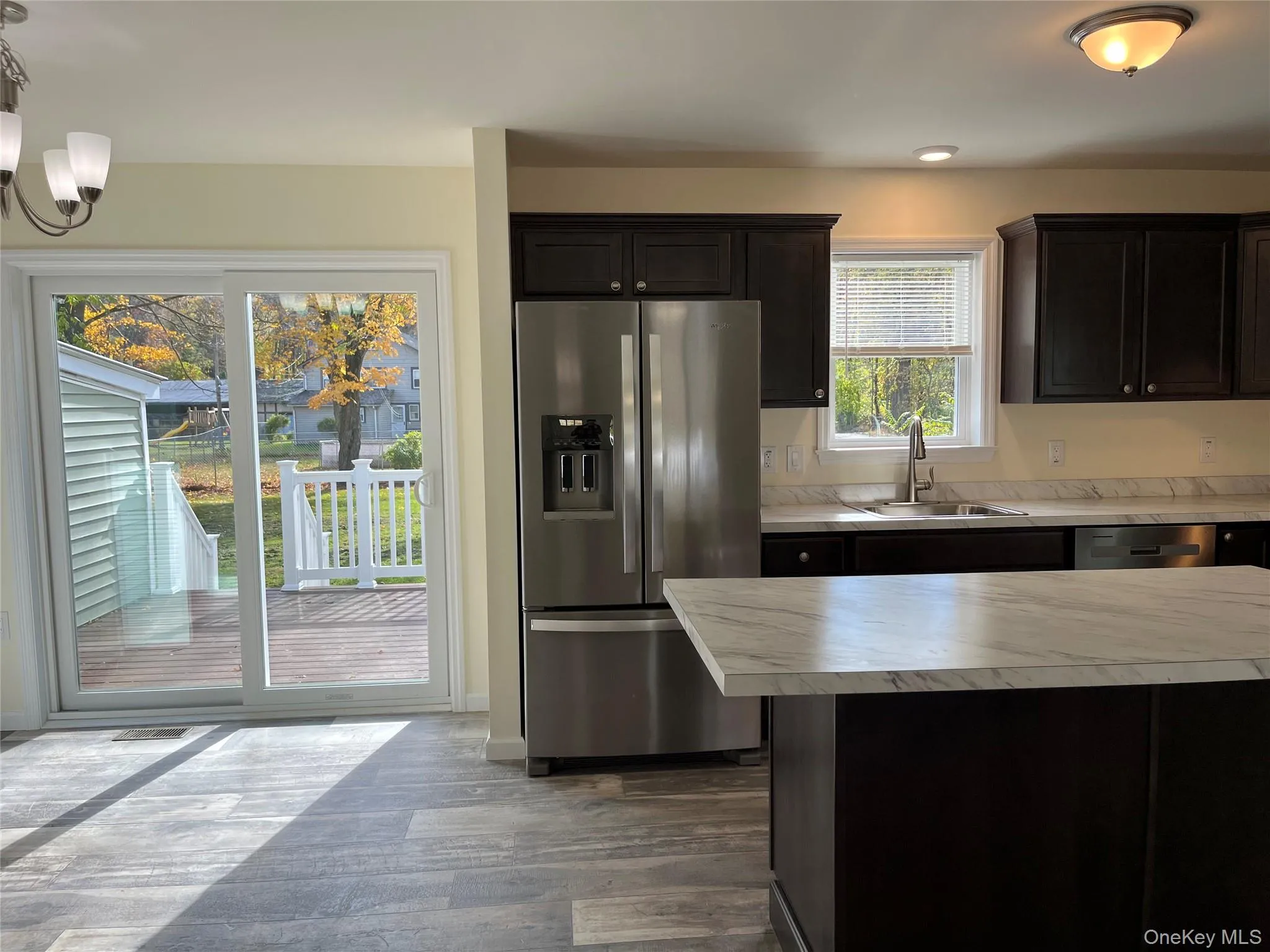 Kitchen with appliances with stainless steel finishes, light countertops, dark wood finished floors, and dark brown cabinetry Kitchen with appliances with stainless steel finishes, light countertops, dark wood finished floors, and dark brown cabinetry