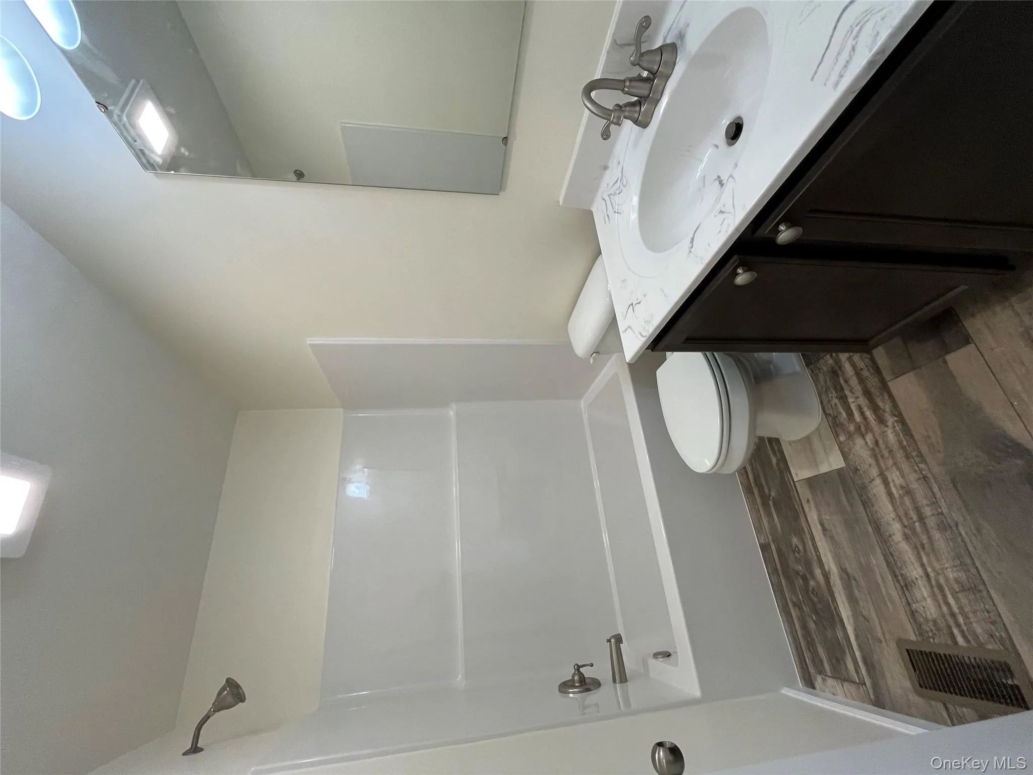 Full bathroom with vanity, shower combination, and dark wood-style floors Full bathroom with vanity, shower combination, and dark wood-style floors