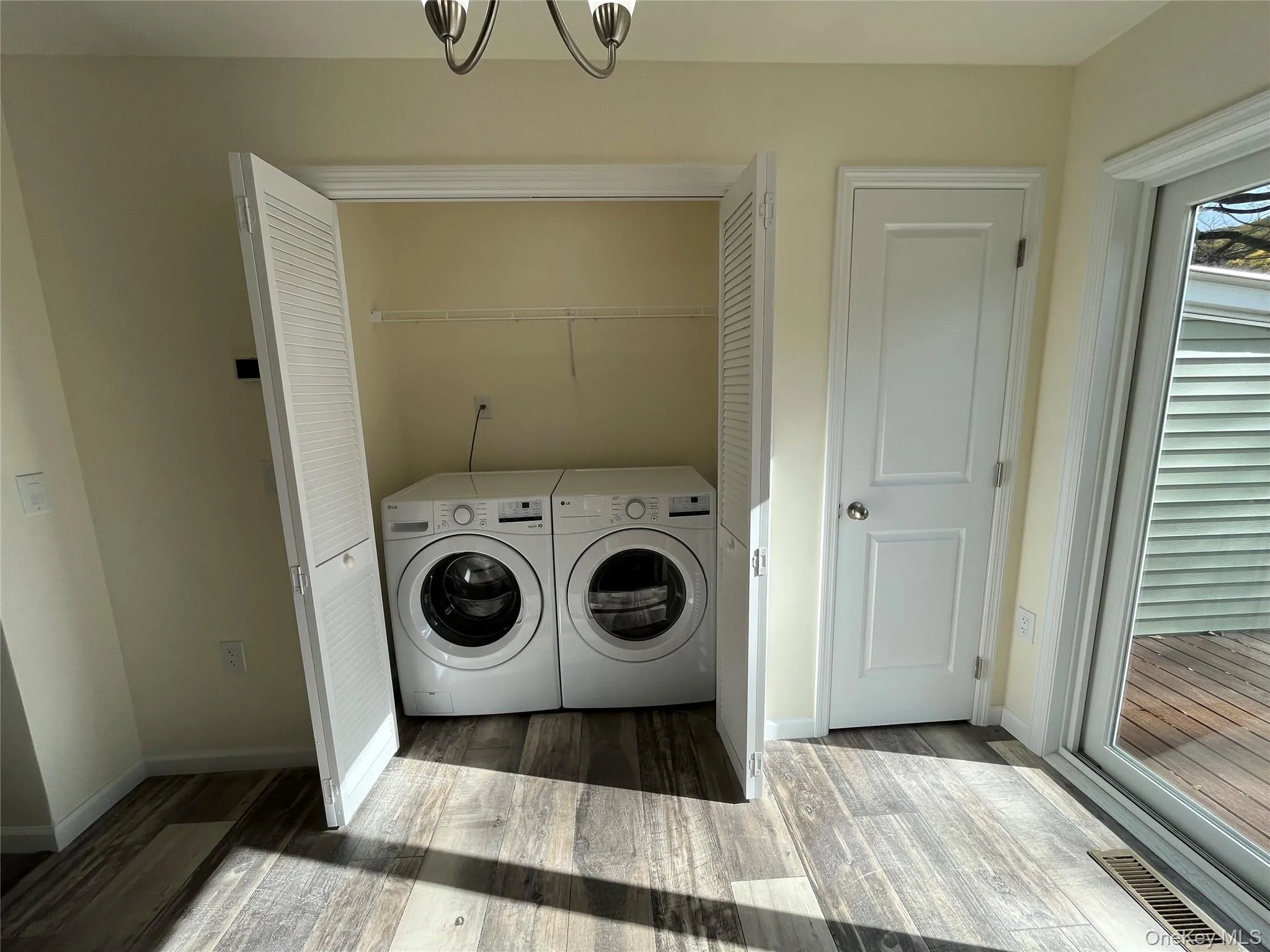 Laundry room featuring wood finished floors, washer and clothes dryer, and a chandelier Laundry room featuring wood finished floors, washer and clothes dryer, and a chandelier