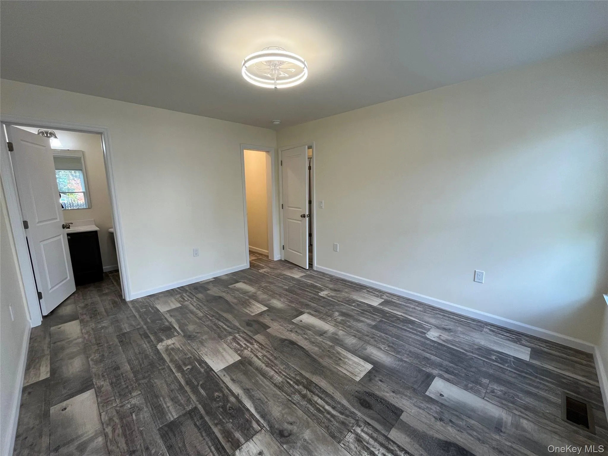 Unfurnished bedroom featuring dark wood finished floors and connected bathroom Unfurnished bedroom featuring dark wood finished floors and connected bathroom